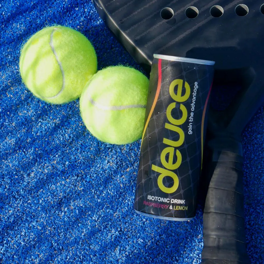 Two tennis balls and a racket on a blue court.